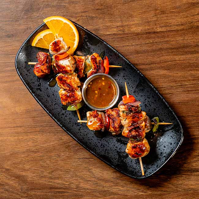Two grilled meat skewers with veggies and sauce—perfect food for private events or parties.