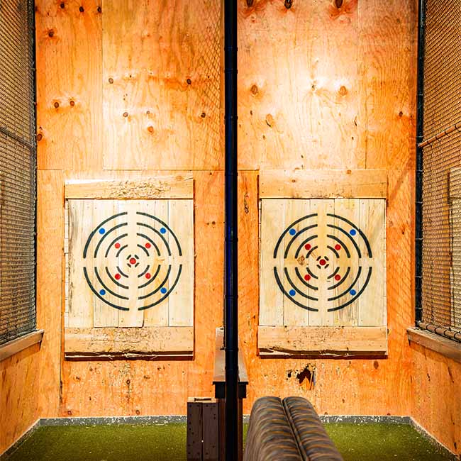 Two wooden axe throwing targets stand in a wood-paneled arcade in North Liberty, Iowa.